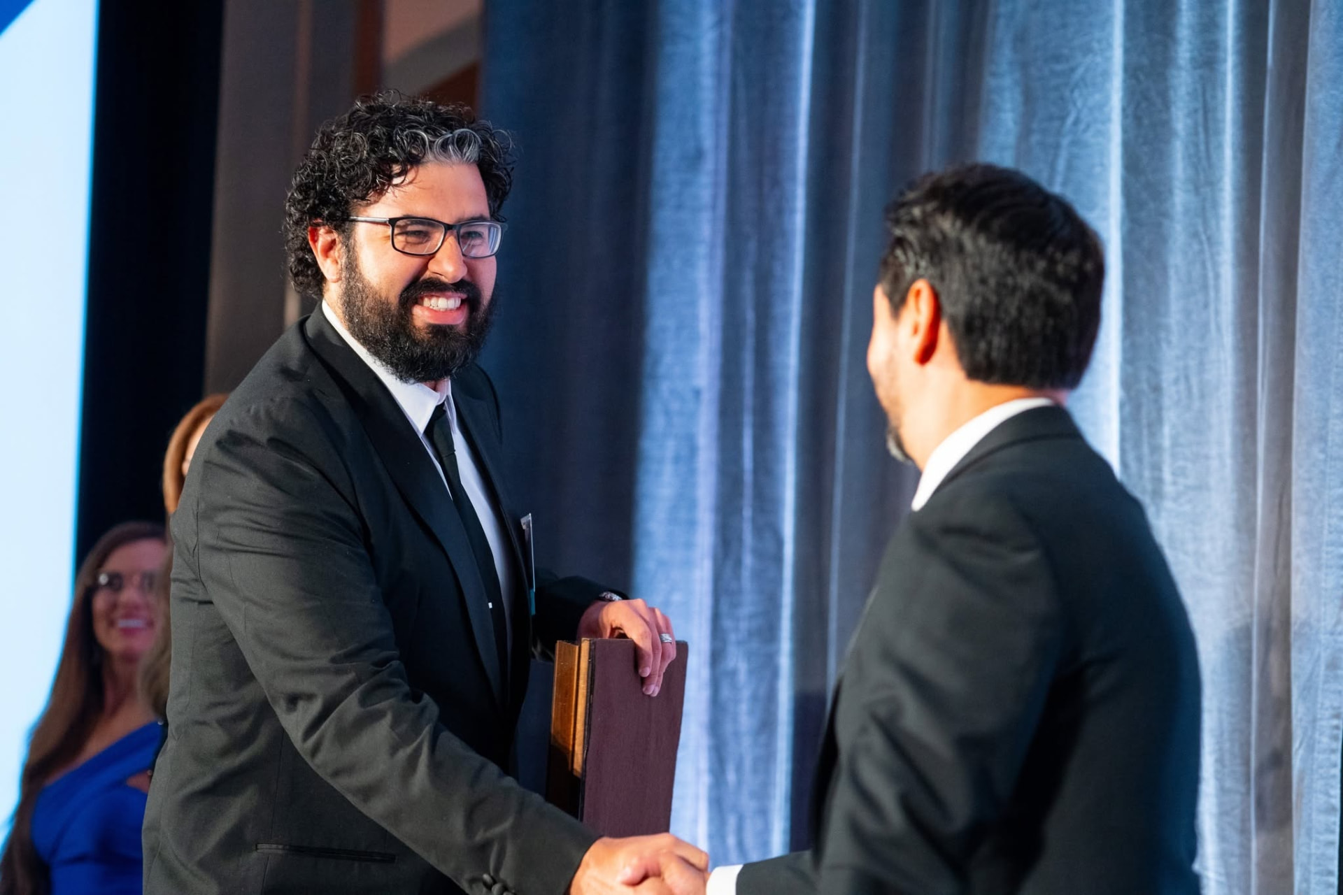 Oscar Quesada shaking hands as Lifedge accepts the West Michigan Hispanic Business of the Year award